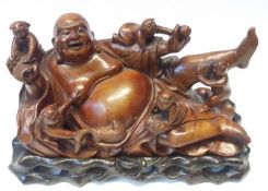 A Chinese Hardwood Figure of a reclining Priest or Buddha with children, all with inlaid eyes,