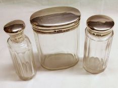 A group of three facetted Glass Toiletry Bottles, with plain hallmarked Silver Lids (with