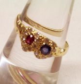 A mid grade yellow metal Double Heart Ring set with a small Ruby and small mid blue Sapphire,