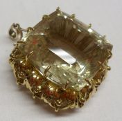 An unmarked precious metal Pendant featuring a large cushion shaped Citrine within a pierced foliate