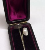 A case containing two Stickpins, one with Pearl finial, the other with white metal disc finial (2)