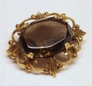 A hallmarked 9ct Gold shaped rolled edge Brooch featuring a smoky Quartz oval stone to the centre,