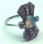 An unmarked precious metal large Dress Ring, set to the centre with an Opal flanked by small