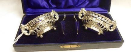 A cased pair of Edwardian ornate oval Salts, heavily embossed and pierced with scrolls and foliate