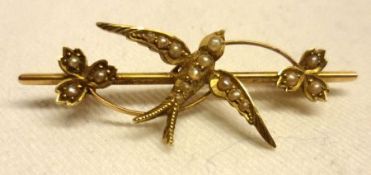 An Edwardian period mid-grade precious metal Brooch featuring a Seed Pearl set swallow and floral