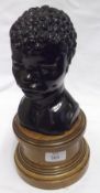 A carved Ebony head and shoulders Bust of a Negro Child, raised on a Satinwood Stand, 12” high