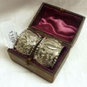 A late Victorian Leather Cased pair of Napkin Rings with crimped edges and foliate embossed centres,