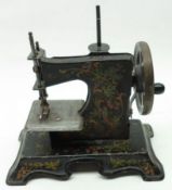 An early 20th Century Child’s Tinplate Sewing Machine, black painted decorated with birds and