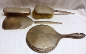 A group of four Silver backed Dressing Table pieces including two Hand Mirrors, (one with cracked