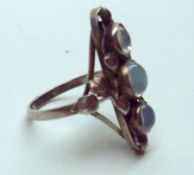 An art nouveau style white metal three Moonstone Ring in large foliate and pierced setting,