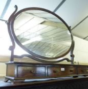 A Mahogany Large Toilet Mirror with oval mirror back, raised on a bowed base fitted with three