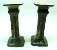 A pair of Royal Doulton Candlesticks decorated with a Winter scene with distant church (repairs to