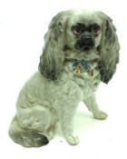 A late 19th Century China Model of a King Charles Spaniel, decorated in grey with a blue collar,