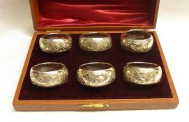 A cased set of six Edwardian Napkin Rings of plain circular form with elaborate foliate