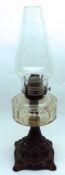 A late Victorian Oil Lamp on cast pierced metal base, clear glass font and clear glass chimney,
