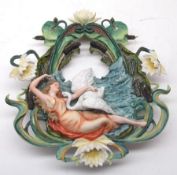 A 20th Century Continental Wall Plaque modelled as a young maiden with swan surrounded by water