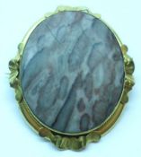 A Victorian Gold framed oval Brooch with applied wavy mounts to the edge, stone set centre, and