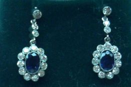 A pair of unmarked precious Metal centre Sapphire and Diamond surround drop Earrings, the centre