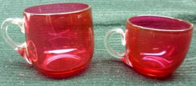 A pair of Cranberry Glass Tot Cups with clear glass handles