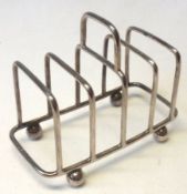 An Edward VII small wirework Toast Rack of five bars with central carry handle, supported on four