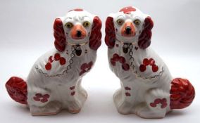 A pair of Staffordshire style Models of seated spaniels, decorated in iron red with gilded collars