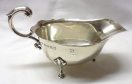 A George V Sauceboat in early Georgian style, with card cut rim, flying scrolled handle and