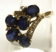 A high grade precious metal Dress Ring featuring a crossover design of five mid blue Sapphires and