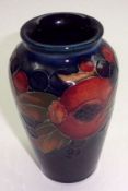 A Moorcroft Small Baluster Vase, decorated with a pomegranate design on a dark blue ground,