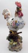 A European Planter modelled as a Cockerel, decorated in faience colours, standing on a floral and