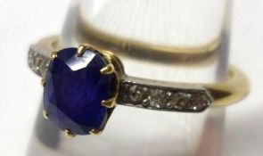 A high grade precious metal centre oval Mid-Blue Sapphire Ring, the shoulders set to each side