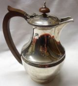 A George V Hot Water Jug of plain circular baluster form, with reeded body band and top, composition