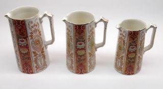 A graduated set of three Ford & Sons Jugs of spreading cylindrical form, each decorated in colours