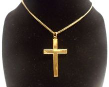 A plain yellow metal Cross, stamped “9ct”, mounted on a yellow metal trace chain, stamped “9ct”