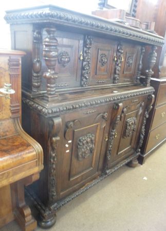 A Victorian Gothic Carved Oak Court Cupboard, the top section with three doors with lion mask