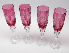 A set of four Bohemian style Champagne Flutes, all etched with foliage and berries on cranberry