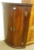 An early 19th Century Mahogany Bow Front Two Door Corner Cupboard, the interior fitted with three