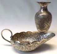 A group of three foreign white metal wares comprising:  An elaborately engraved Sauce Boat, 6” long,