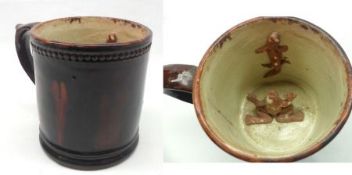 A Staffordshire treacle glazed Frog Mug, inset with a frog and a lizard (restored rim), 4 ¾” high