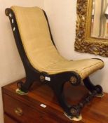 An early 19th Century Ebonised Framed Nursing Chair of “X” frame form, decorated with gilt metal