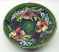 A Moorcroft Large Circular Dish, decorated with an orchid design on a green ground, impressed