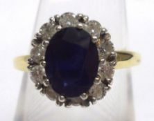 A hallmarked 18ct Gold centre Dark Blue Sapphire and ten small brilliant cut Diamond surround