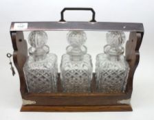 An Oak and Silver Plated Mounted Tantalus, fitted with three moulded glass decanters, 15” wide