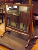 A late 19th/early 20th Century Mahogany Swing Mirror, crested with brass urn finials and raised on