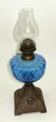 A late 19th Century Oil Lamp with blue glass font, raised on a pierced cast metal base, 15 ½” high