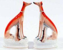 A pair of Staffordshire Models of large seated Greyhounds, each decorated in iron red and with