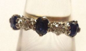 A high grade precious metal three Mid-Blue Sapphire and two small brilliant cut Diamond Ring,