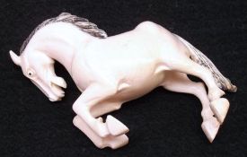 A small Carved Ivory Model of a prancing horse, black painted mane and tail, 4 ½” long