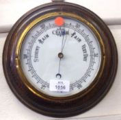 An early 20th Century Oak Framed Circular Aneroid Barometer, with opaque glass dial, brass bezel,