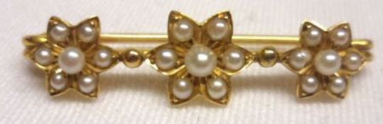 An unmarked Victorian Gold Pin formed Bar Brooch, set with three rosettes of Seed Pearls,