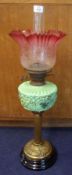 A Victorian Oil Lamp, the later crimped and cranberry tinted glass shade over moulded green glass